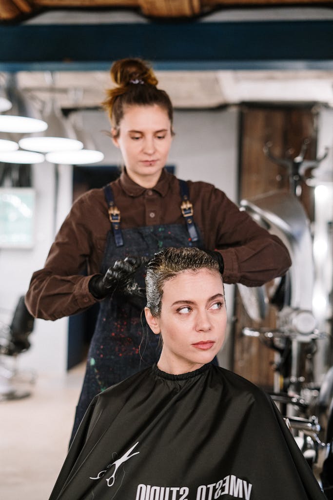 Hairdresser styling a woman's hair in a modern salon setting.