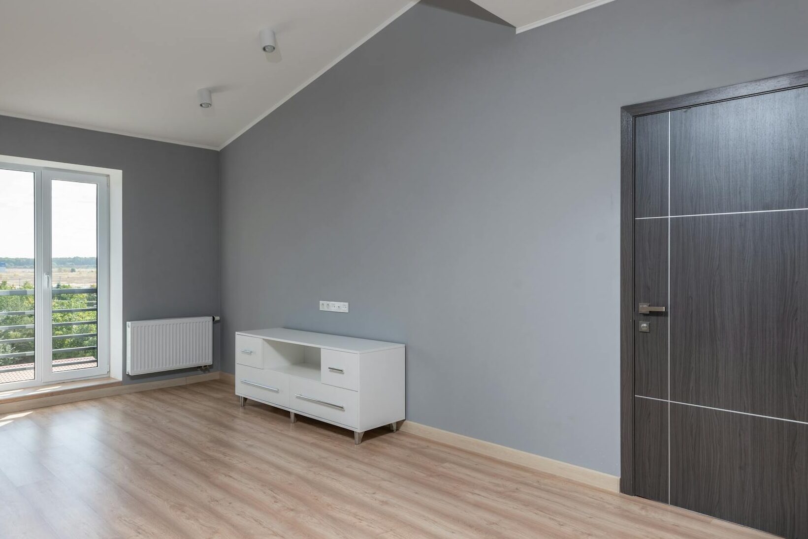 Bright and empty modern room with hardwood floors and large window view.